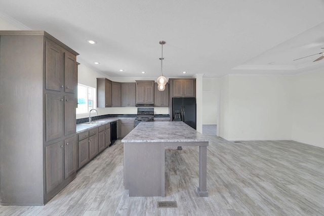 kitchen with light wood-type flooring, decorative light fixtures, black appliances, a kitchen island, and ceiling fan