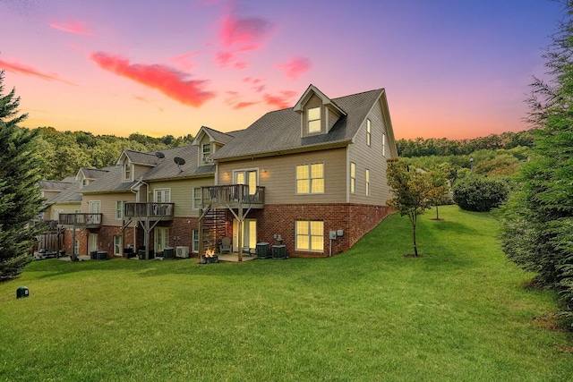 back house at dusk with a yard, central AC, and a wooden deck