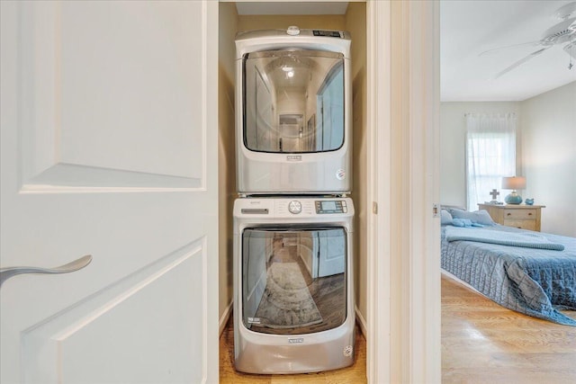 laundry area featuring stacked washer and clothes dryer and light hardwood / wood-style floors