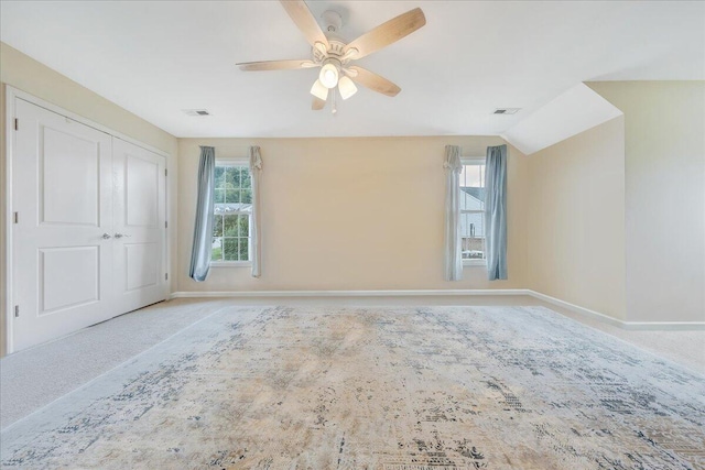 carpeted spare room with ceiling fan and vaulted ceiling