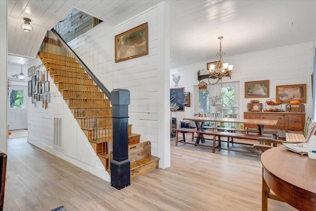 stairs featuring hardwood / wood-style floors and a chandelier