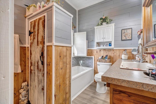 bathroom featuring a tub to relax in, toilet, wood walls, vanity, and hardwood / wood-style flooring