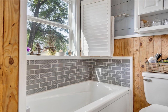 bathroom with wooden walls, toilet, and a bathtub