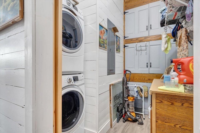 laundry area featuring stacked washer / drying machine and light hardwood / wood-style floors