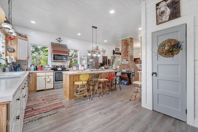 kitchen featuring a kitchen bar, sink, a center island, stainless steel appliances, and light hardwood / wood-style floors