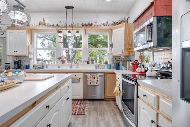 kitchen featuring tasteful backsplash, decorative light fixtures, stainless steel appliances, and a healthy amount of sunlight