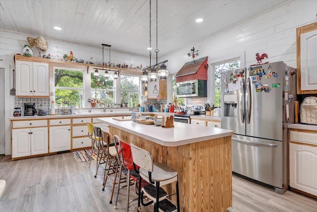 kitchen featuring a kitchen island, appliances with stainless steel finishes, a wealth of natural light, and light wood-type flooring