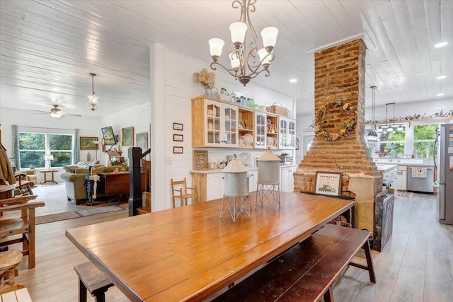 dining space with ceiling fan with notable chandelier, wood ceiling, and light hardwood / wood-style flooring