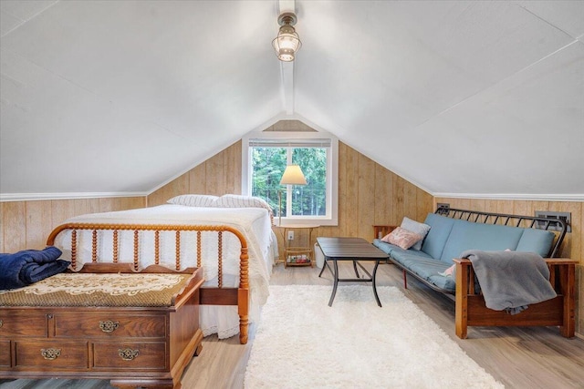 bedroom featuring lofted ceiling, light hardwood / wood-style flooring, and wood walls