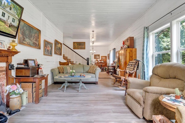 living room with an inviting chandelier, brick wall, and light hardwood / wood-style flooring