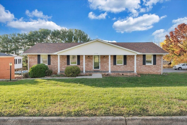 ranch-style home featuring covered porch and a front yard