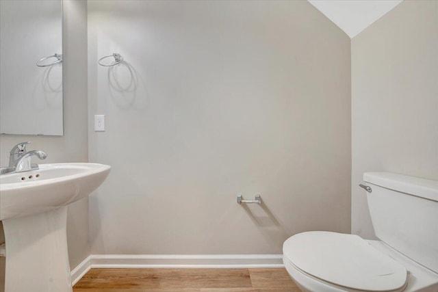 bathroom featuring sink, hardwood / wood-style floors, vaulted ceiling, and toilet