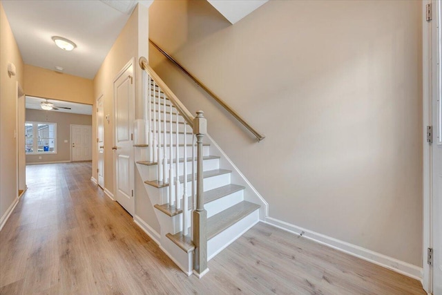 stairs with hardwood / wood-style floors and ceiling fan