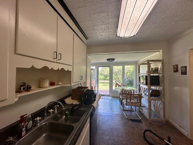 kitchen featuring ornamental molding, sink, and white cabinetry