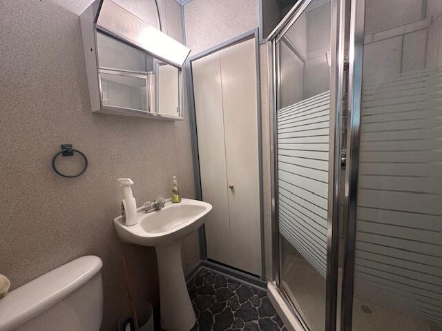 bathroom featuring toilet and an enclosed shower