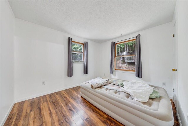 unfurnished living room with a wealth of natural light, a textured ceiling, and dark hardwood / wood-style flooring