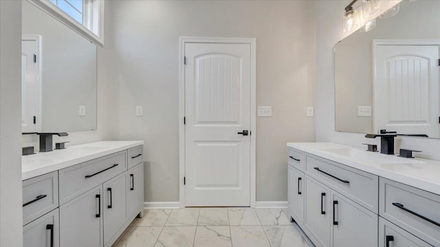 full bathroom featuring marble finish floor, two vanities, and a sink