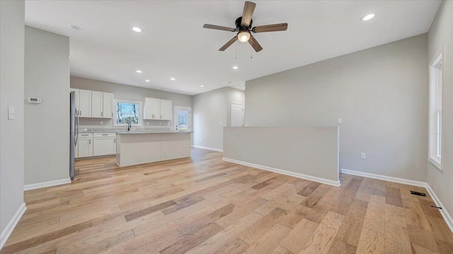 kitchen with light countertops, light wood-style floors, open floor plan, white cabinets, and a kitchen island