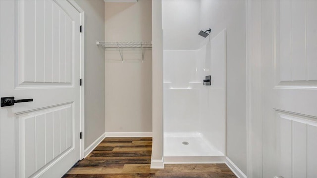 bathroom with wood finished floors, a shower stall, and baseboards