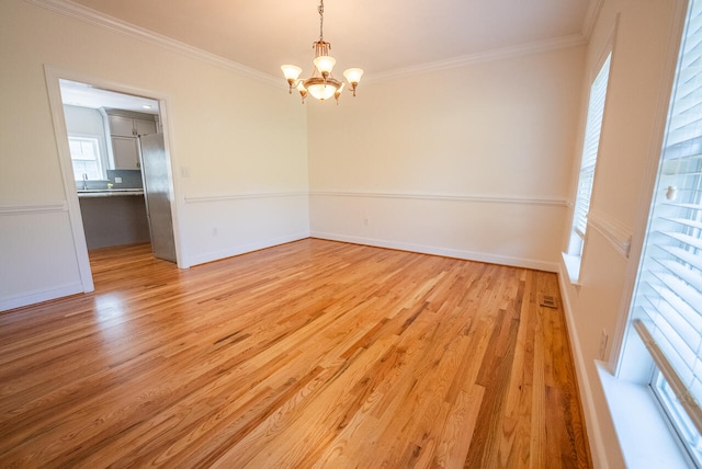 unfurnished room with ornamental molding, a notable chandelier, and light hardwood / wood-style flooring