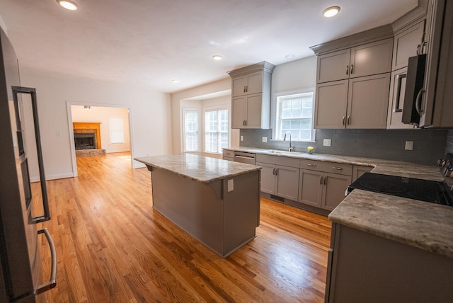 kitchen featuring a kitchen island, light hardwood / wood-style flooring, gray cabinets, a fireplace, and black range with electric cooktop