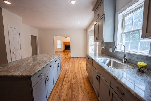 kitchen with light stone countertops, light hardwood / wood-style floors, sink, and decorative backsplash