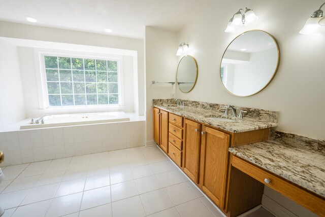 bathroom featuring tile patterned flooring, vanity, and a relaxing tiled tub