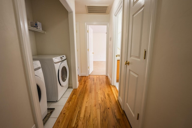 laundry room featuring washing machine and clothes dryer and light hardwood / wood-style floors