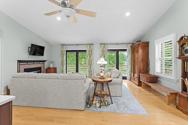 living room with light hardwood / wood-style floors, a tile fireplace, and a healthy amount of sunlight