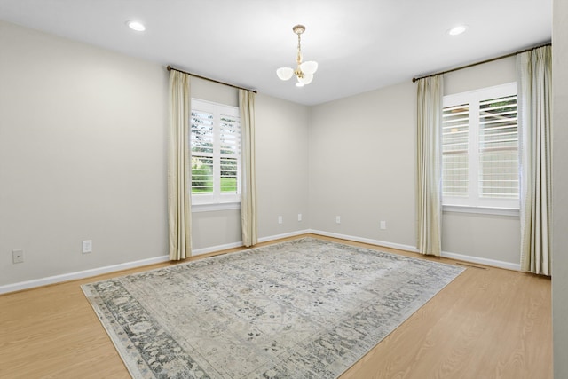 unfurnished room with light hardwood / wood-style floors and a chandelier