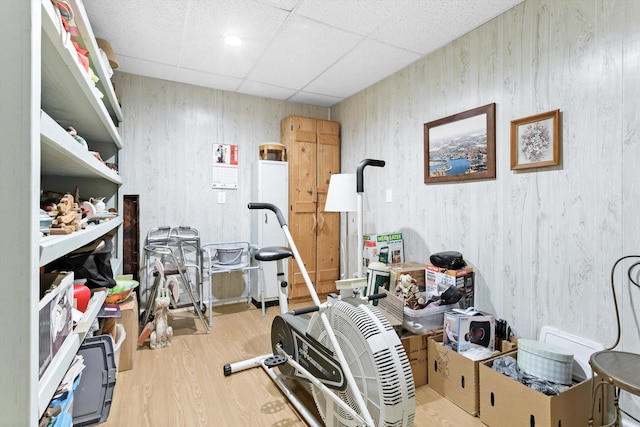 exercise area with light hardwood / wood-style floors and a paneled ceiling