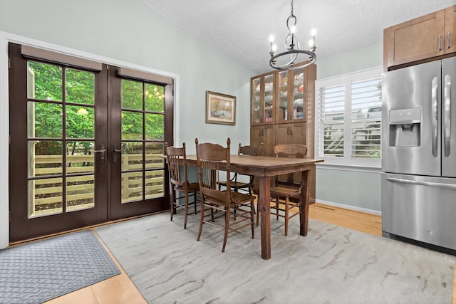 dining area with a notable chandelier, vaulted ceiling, light hardwood / wood-style flooring, and a wealth of natural light