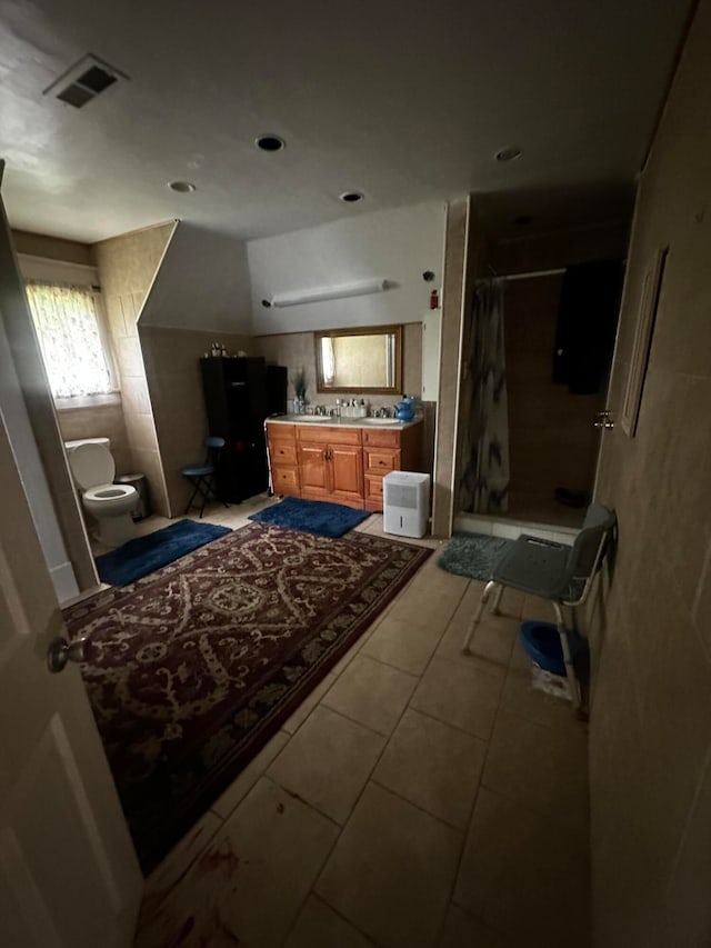 interior space featuring tile patterned flooring, curtained shower, vanity, and toilet