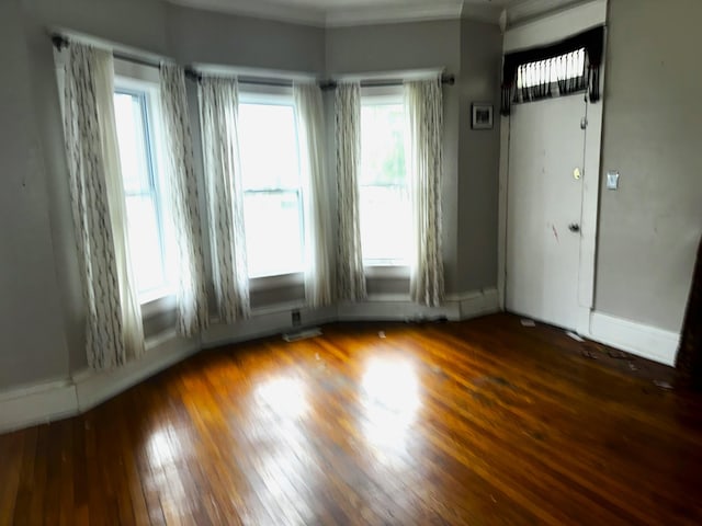 spare room featuring crown molding and dark wood-type flooring