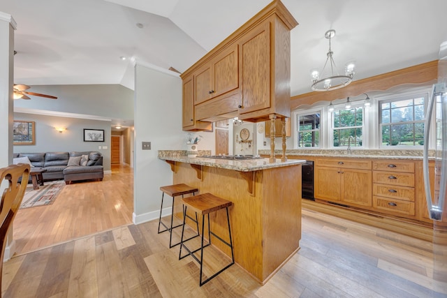 kitchen with light hardwood / wood-style floors, vaulted ceiling, light stone counters, ceiling fan with notable chandelier, and kitchen peninsula