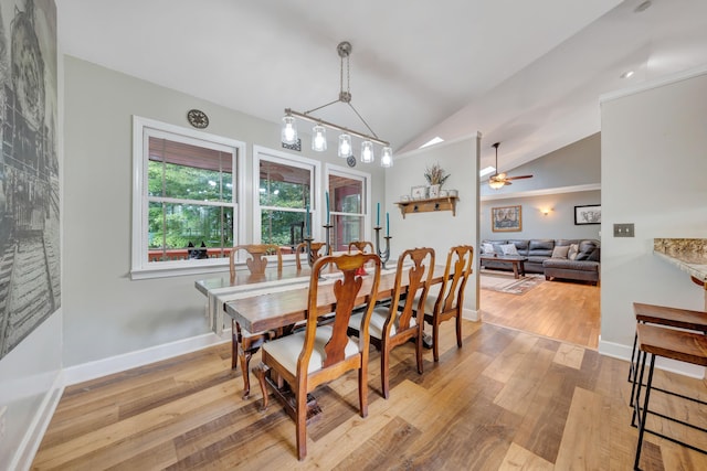 dining space with ceiling fan with notable chandelier, light hardwood / wood-style floors, and vaulted ceiling