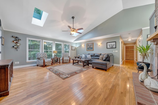 living room featuring ceiling fan, a skylight, light hardwood / wood-style flooring, high vaulted ceiling, and crown molding