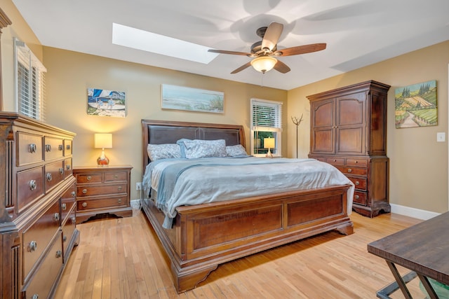 bedroom with light hardwood / wood-style floors, ceiling fan, and a skylight