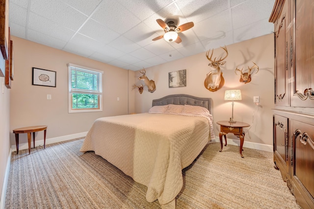 carpeted bedroom with a paneled ceiling and ceiling fan