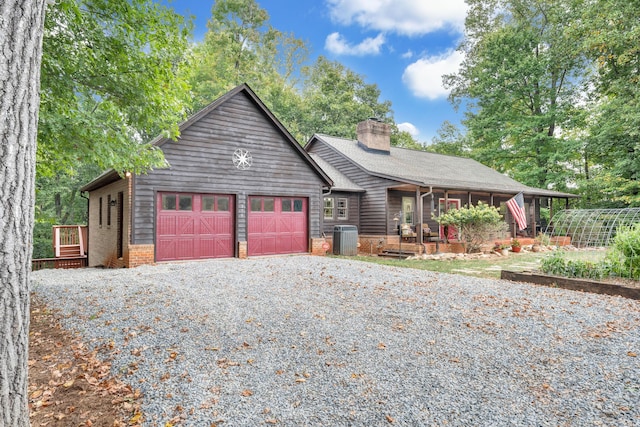 view of front of house featuring cooling unit, covered porch, and a garage