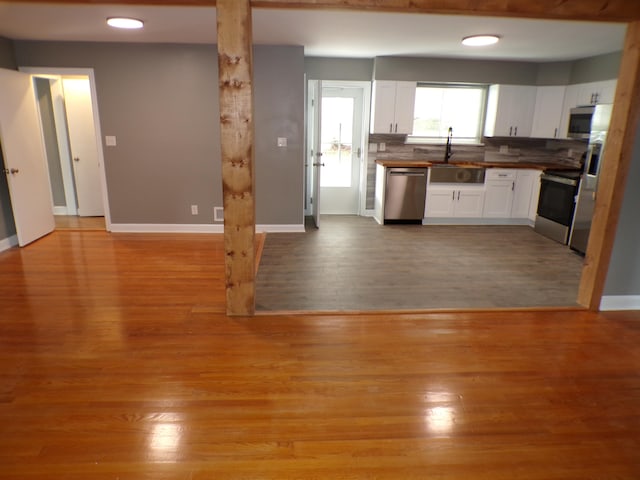 kitchen featuring light wood-type flooring, wood counters, sink, white cabinets, and stainless steel appliances