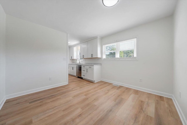 kitchen with white cabinets, light wood-type flooring, sink, and stainless steel dishwasher