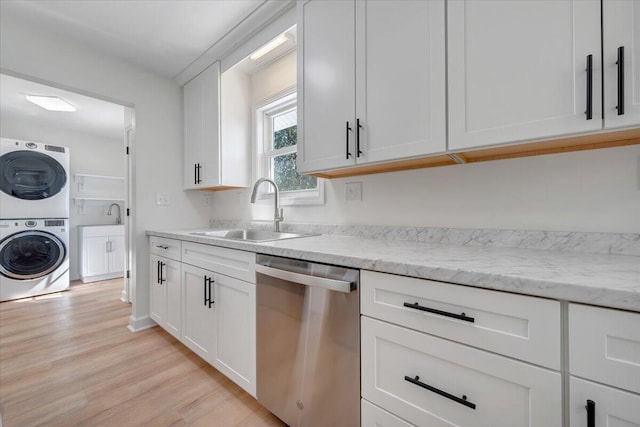 kitchen featuring light hardwood / wood-style floors, stacked washer and clothes dryer, sink, white cabinets, and stainless steel dishwasher