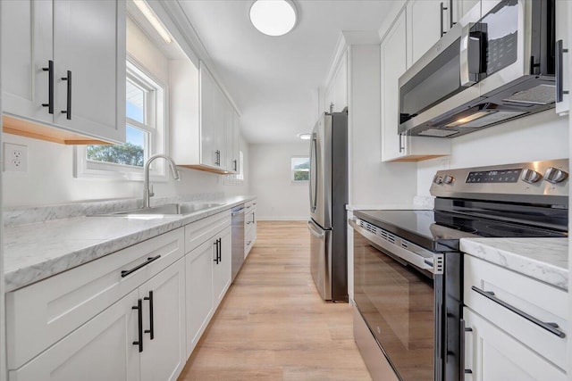 kitchen with light hardwood / wood-style floors, white cabinets, appliances with stainless steel finishes, and sink