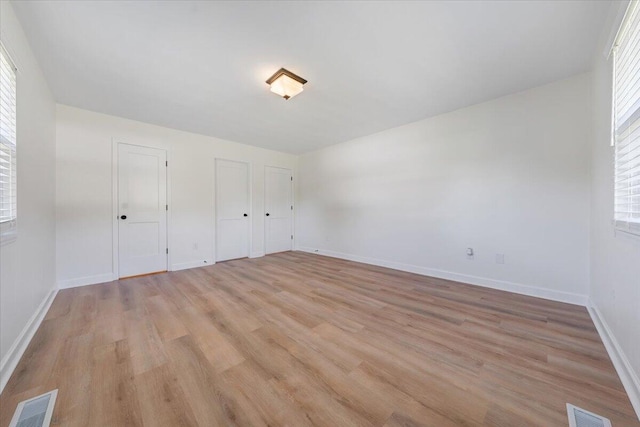 unfurnished bedroom with light hardwood / wood-style flooring and two closets