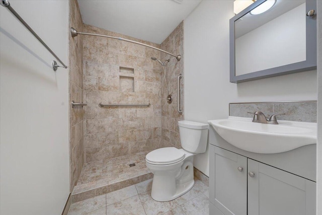 bathroom featuring tile patterned flooring, a tile shower, vanity, and toilet