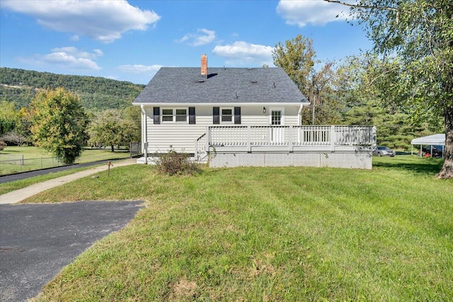 rear view of property with a deck with mountain view and a lawn