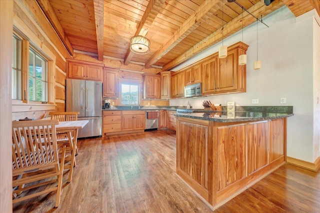 kitchen featuring pendant lighting, beamed ceiling, kitchen peninsula, hardwood / wood-style flooring, and stainless steel appliances