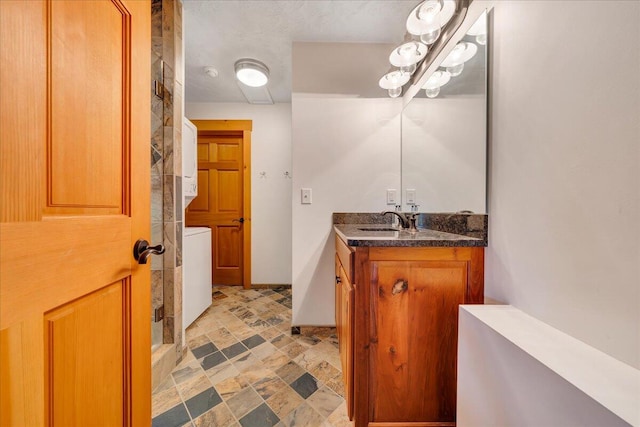 bathroom with stacked washer and clothes dryer, vanity, and a shower with shower door