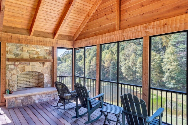 unfurnished sunroom with a stone fireplace, vaulted ceiling with beams, and wood ceiling